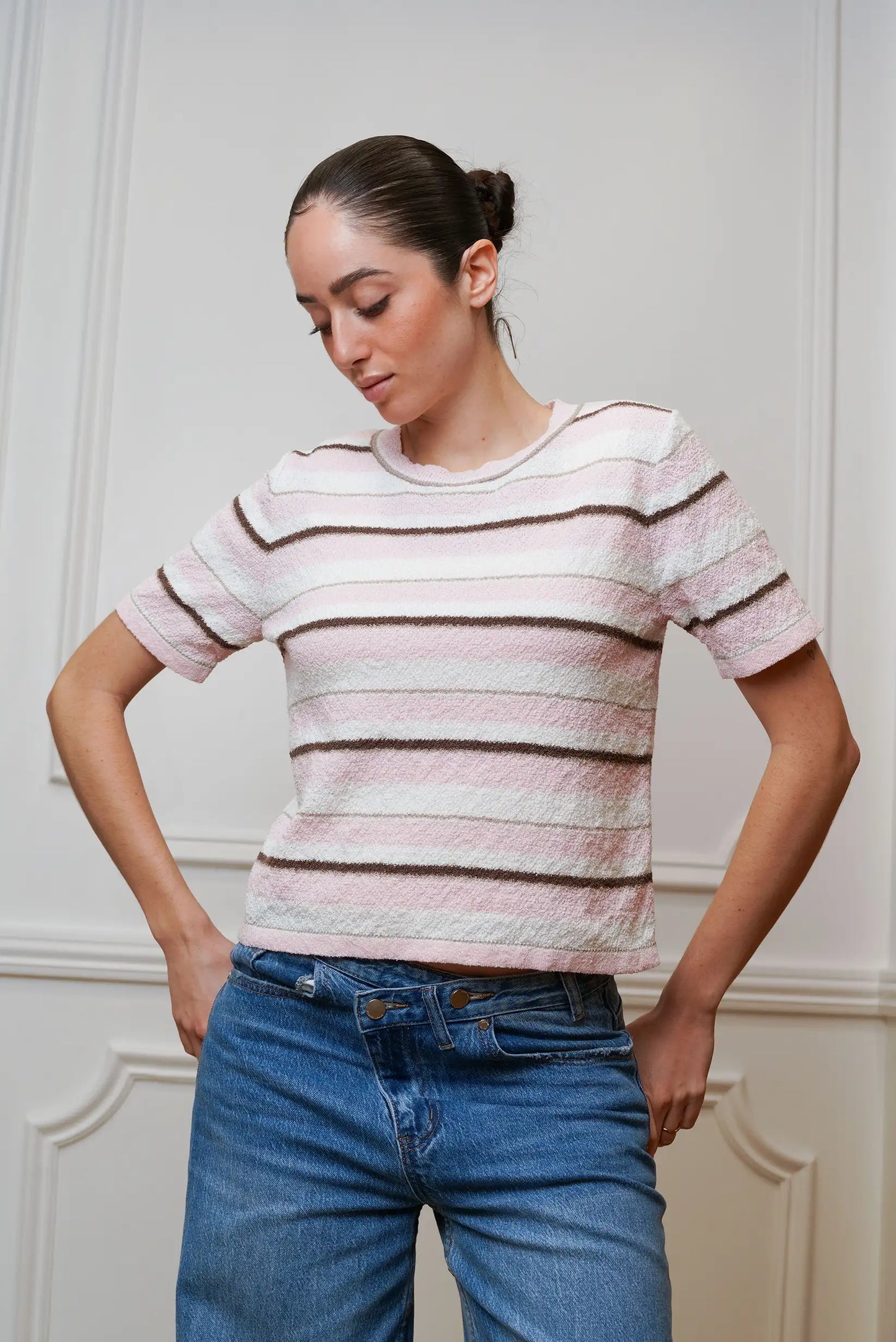 Mujer con camiseta de rayas rosas y marrones de manga corta, combinada con jeans.