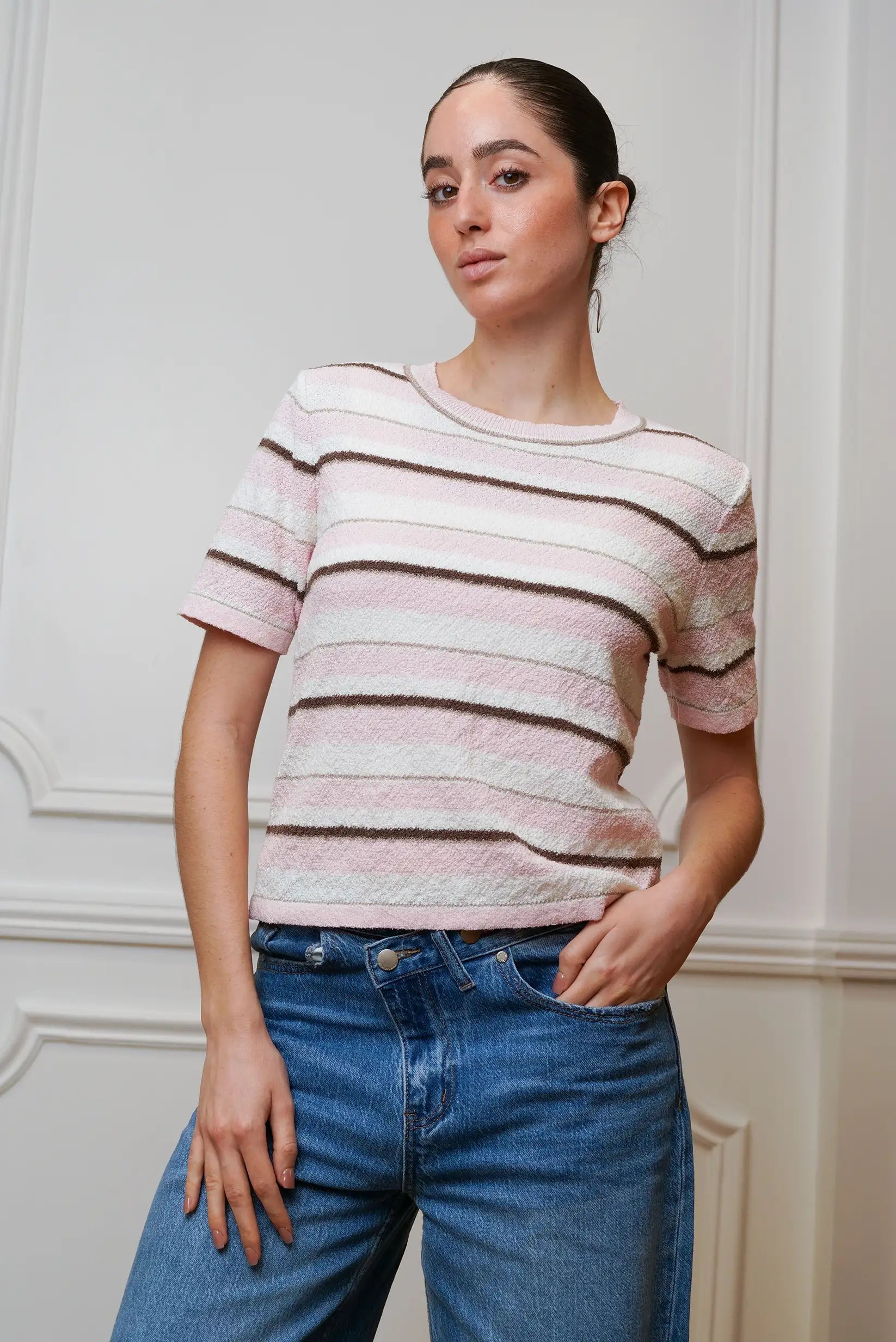 Mujer con top de rayas rosa y blanco de manga corta y jeans en ambiente interior