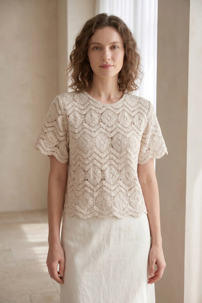 Blusa de encaje beige con mangas cortas y cuello redondo, ideal para looks casuales y estilosos