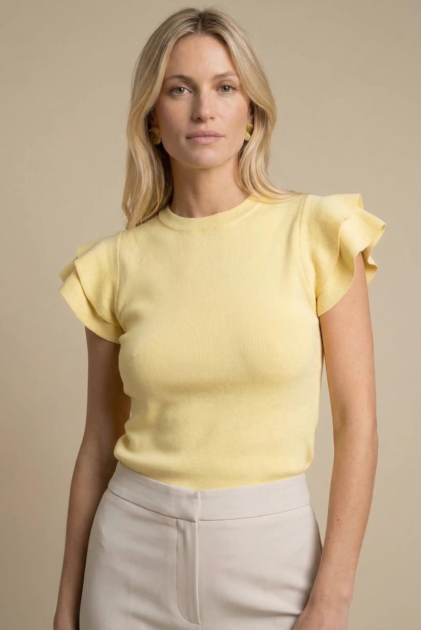 Mujer con top amarillo pastel de manga corta con volantes, estilo casual primavera.
