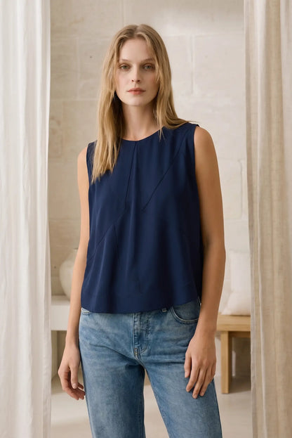 Mujer con top azul sin mangas y jeans, look casual de primavera en interior luminoso