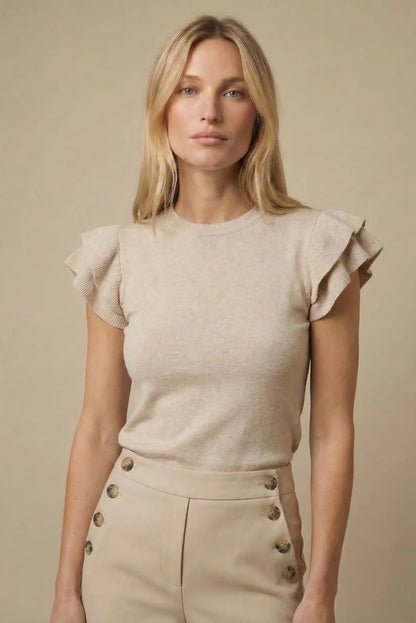 Mujer con top beige de manga corta con volantes y pantalón beige de talle alto, estilo casual femenino