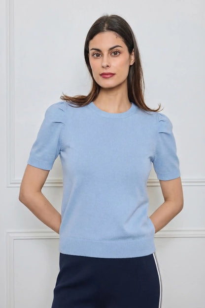 Mujer con top azul pastel de manga corta, look casual primaveral, fondo neutro
