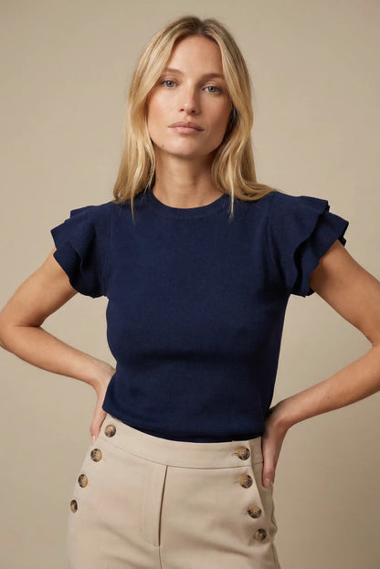 Mujer con top azul marino de manga corta con volantes, ideal para moda casual de primavera.