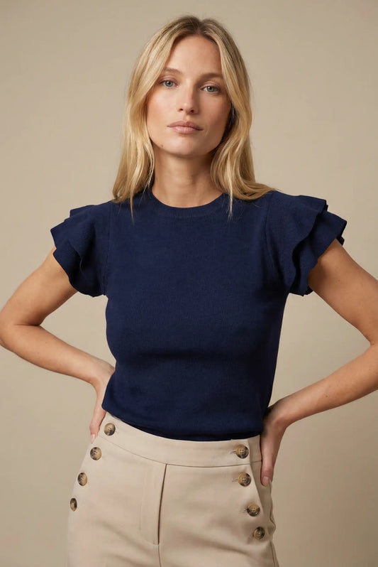 Mujer con top azul marino de manga corta con volantes, ideal para moda casual de primavera.