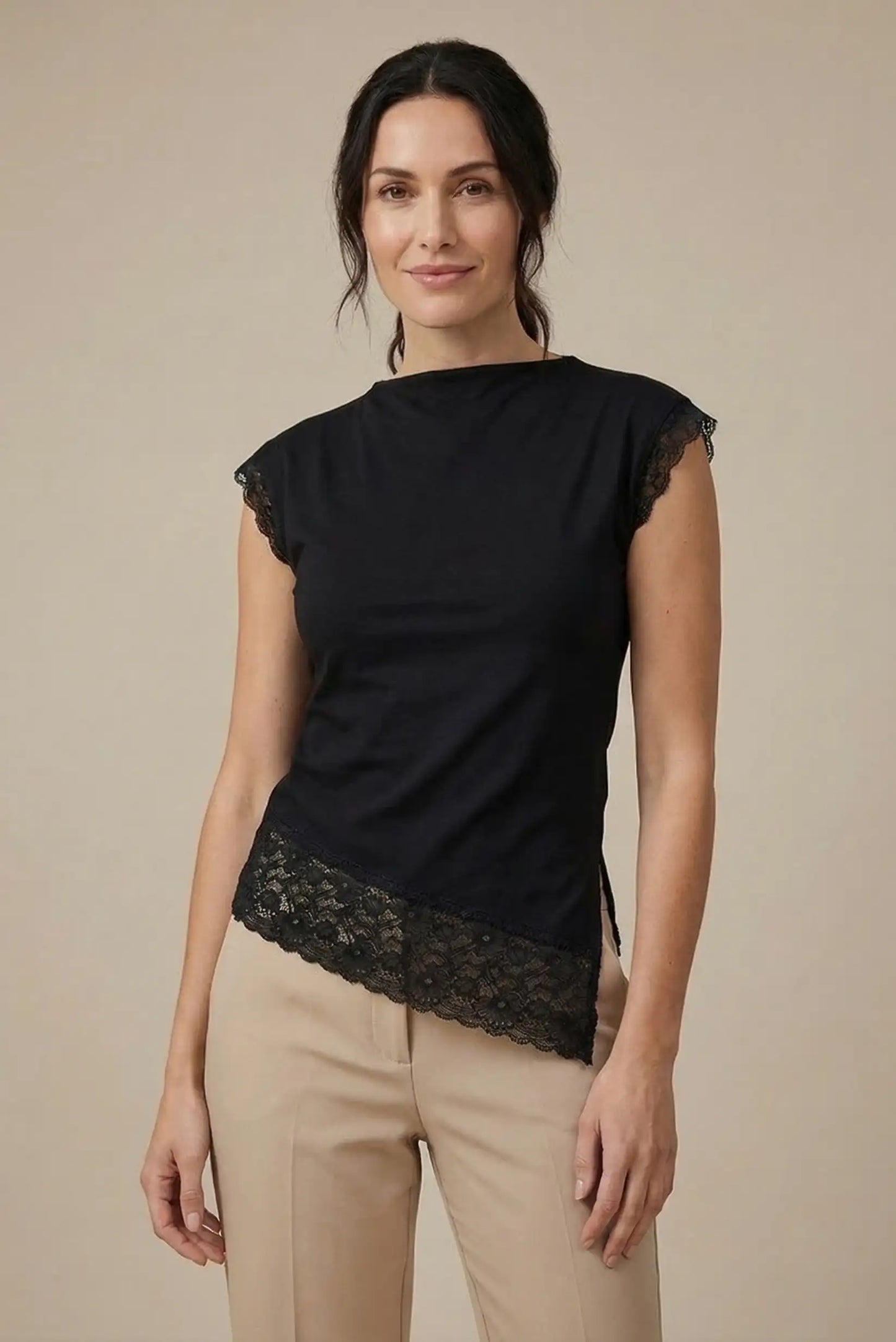 Mujer con top negro de encaje en dobladillo y mangas, look casual de primavera-verano.