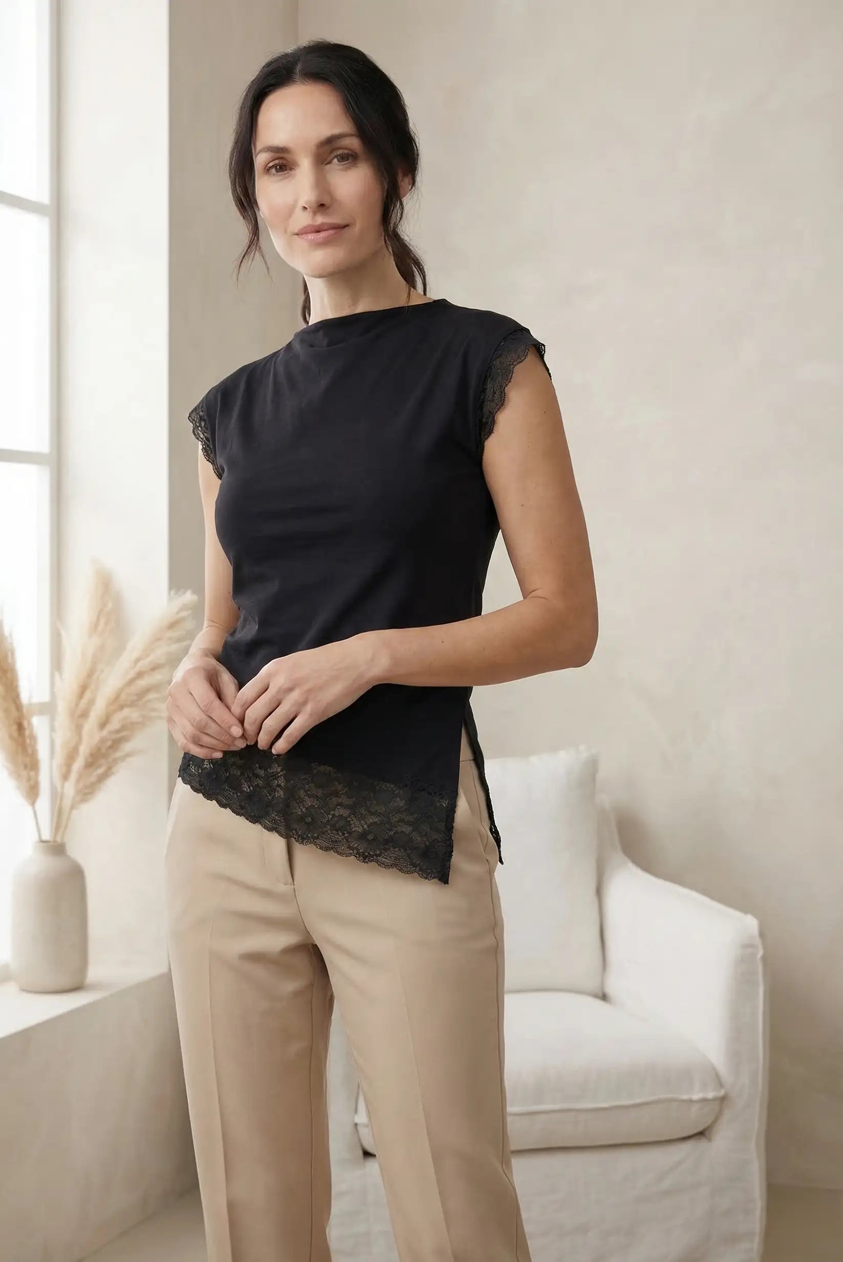 Top mujer negro con encaje, manga corta, estilo casual de primavera, combinado con pantalón beige.