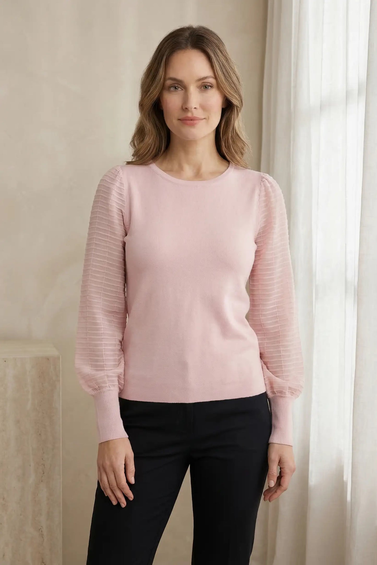Mujer con top rosa pastel de manga larga texturizada, estilo casual primaveral.