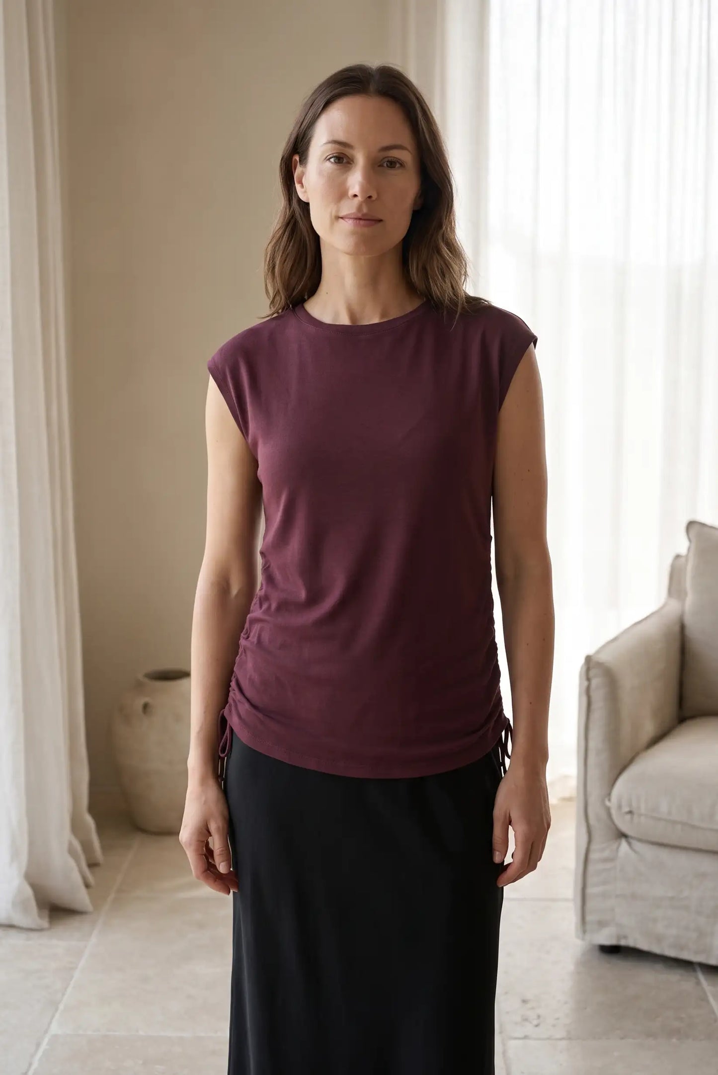 Mujer vistiendo camiseta sin mangas color burdeos y falda larga negra.
