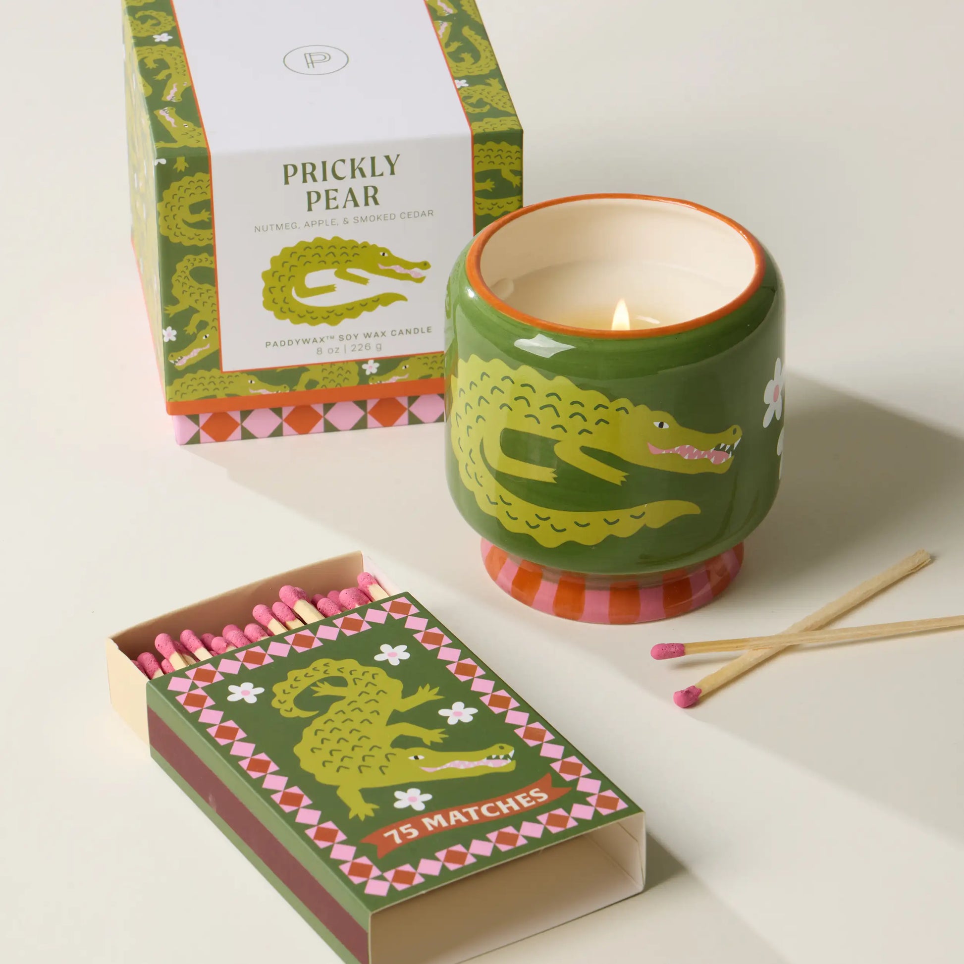 Vela decorativa Paddywax con diseño de cocodrilo verde, cerillas rosas y caja colorida
