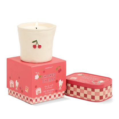 Vela aromática de cereza en cerámica blanca sobre caja rosa, estilo decorativo CHICA del Sur