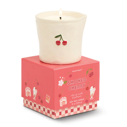 Vela aromática Paddywax de cereza en vaso cerámico blanco sobre caja rosa, CHICA del Sur