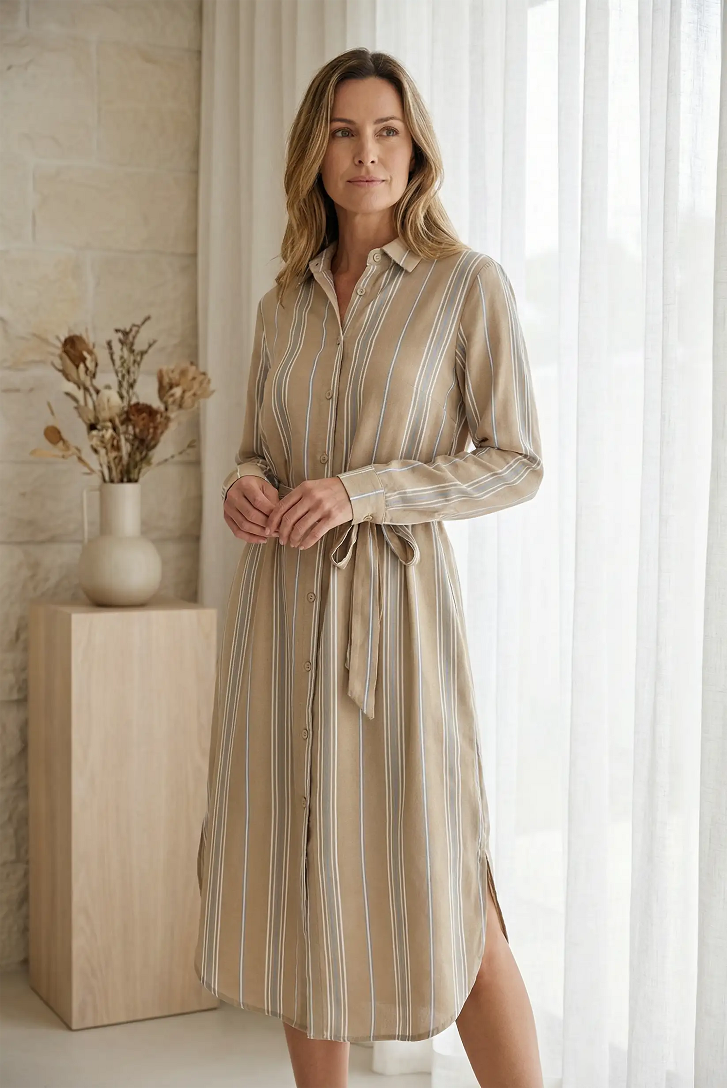 Mujer con vestido camisero de rayas camel y cinturón ajustable, estilo casual elegante.