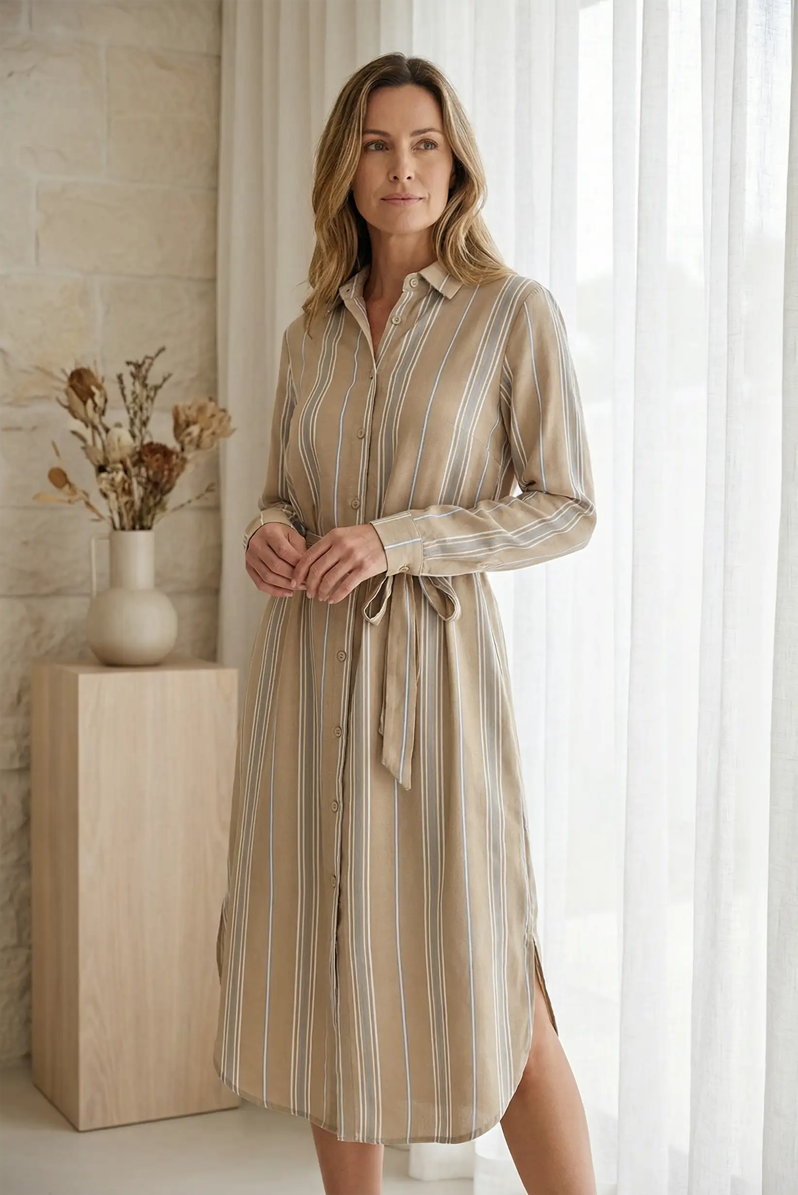 Mujer con vestido camisero de rayas camel y cinturón ajustable, estilo casual elegante.