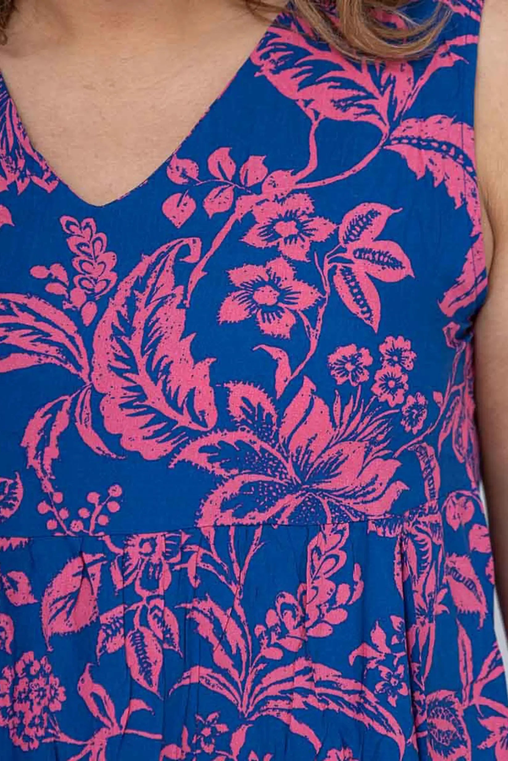 Vestido azul con estampado floral rosa, cuello en V y detalles de pliegues