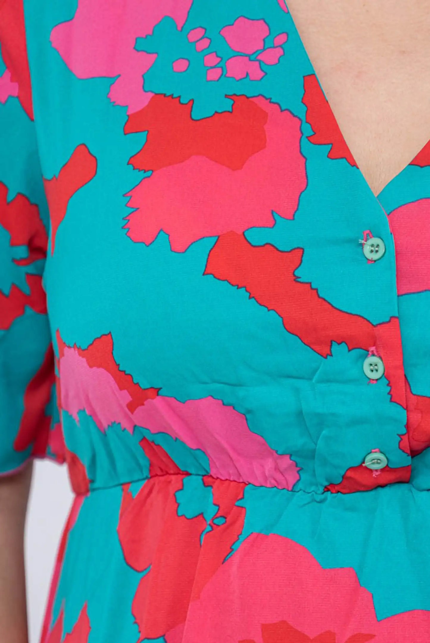 Vestido floral con estampado vibrante en turquesa, rosa y rojo, botones decorativos y corte femenino