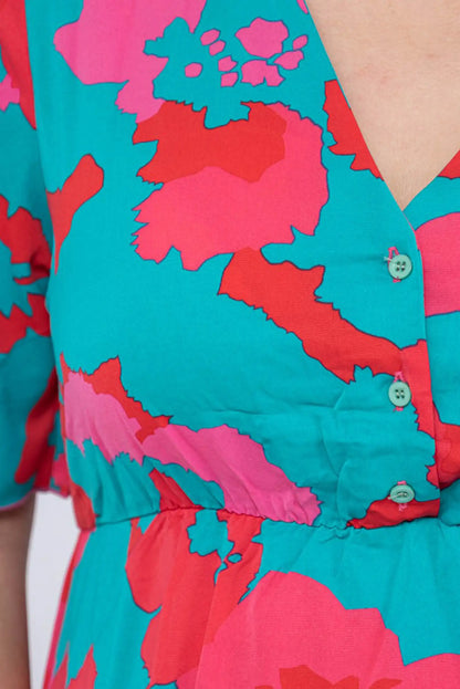 Vestido floral con estampado vibrante en turquesa, rosa y rojo, botones decorativos y corte femenino