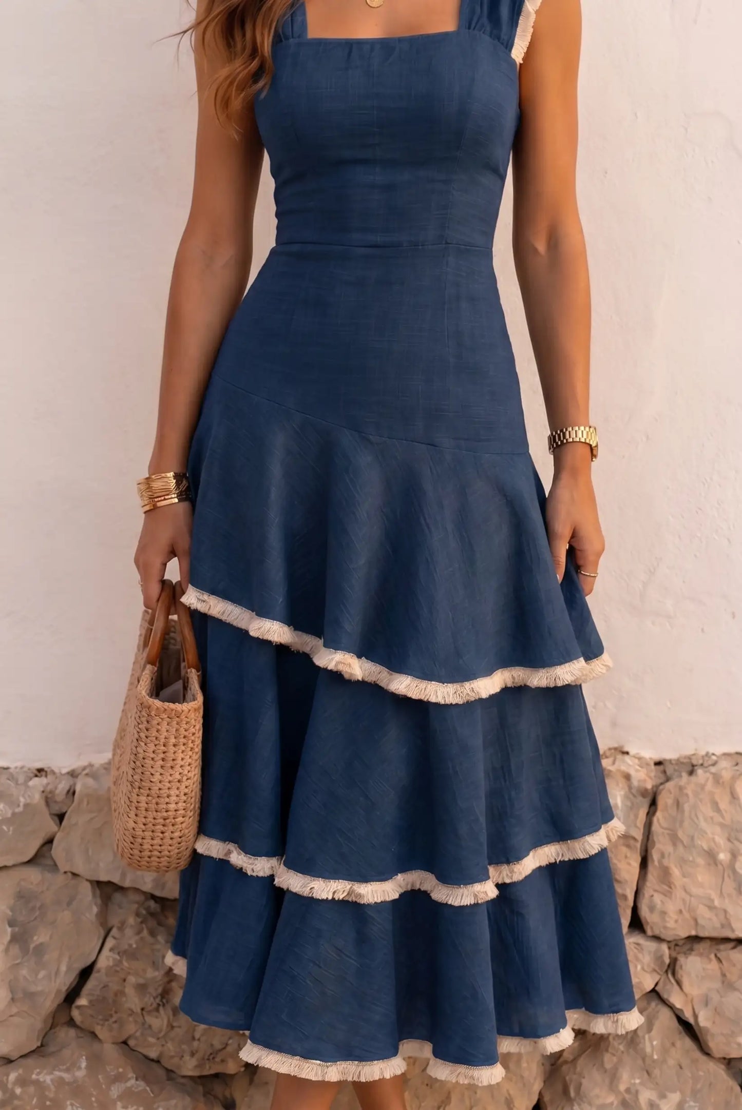 Vestido azul con volantes y borlas, ideal para verano, combinado con bolso de paja y accesorios dorados