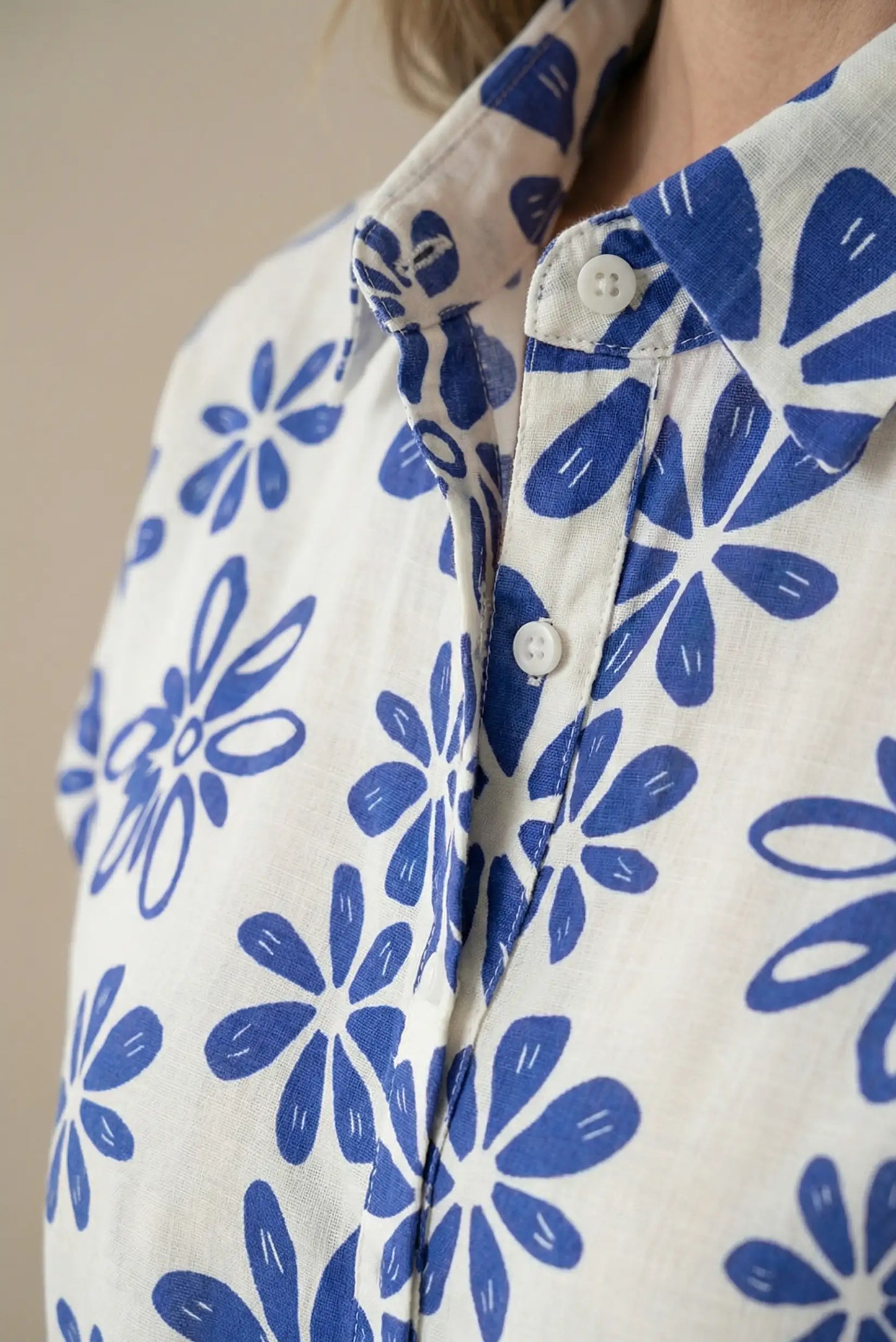 Detalle de vestido blanco con flores azules, manga corta y cuello camisero, estilo casual femenino