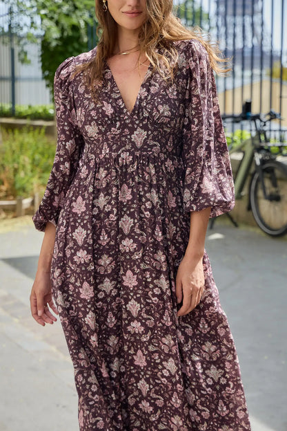 Mujer vistiendo vestido largo color burdeos con estampado floral y escote en V