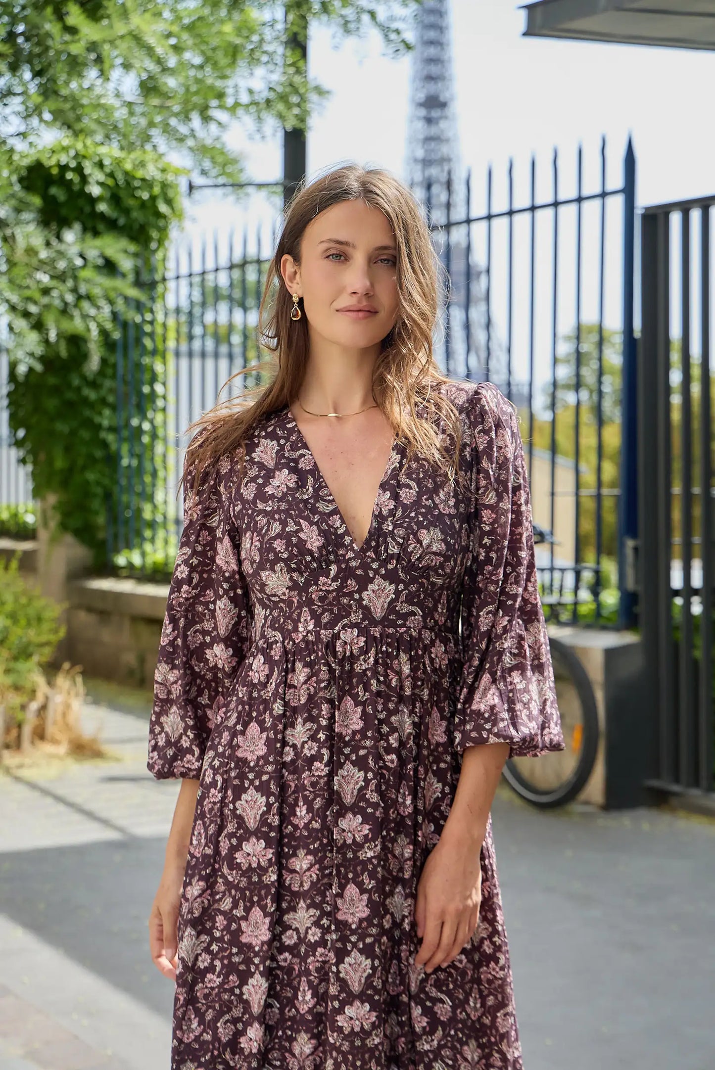 Mujer con vestido largo estampado floral en tonos burdeos y rosa con escote en V