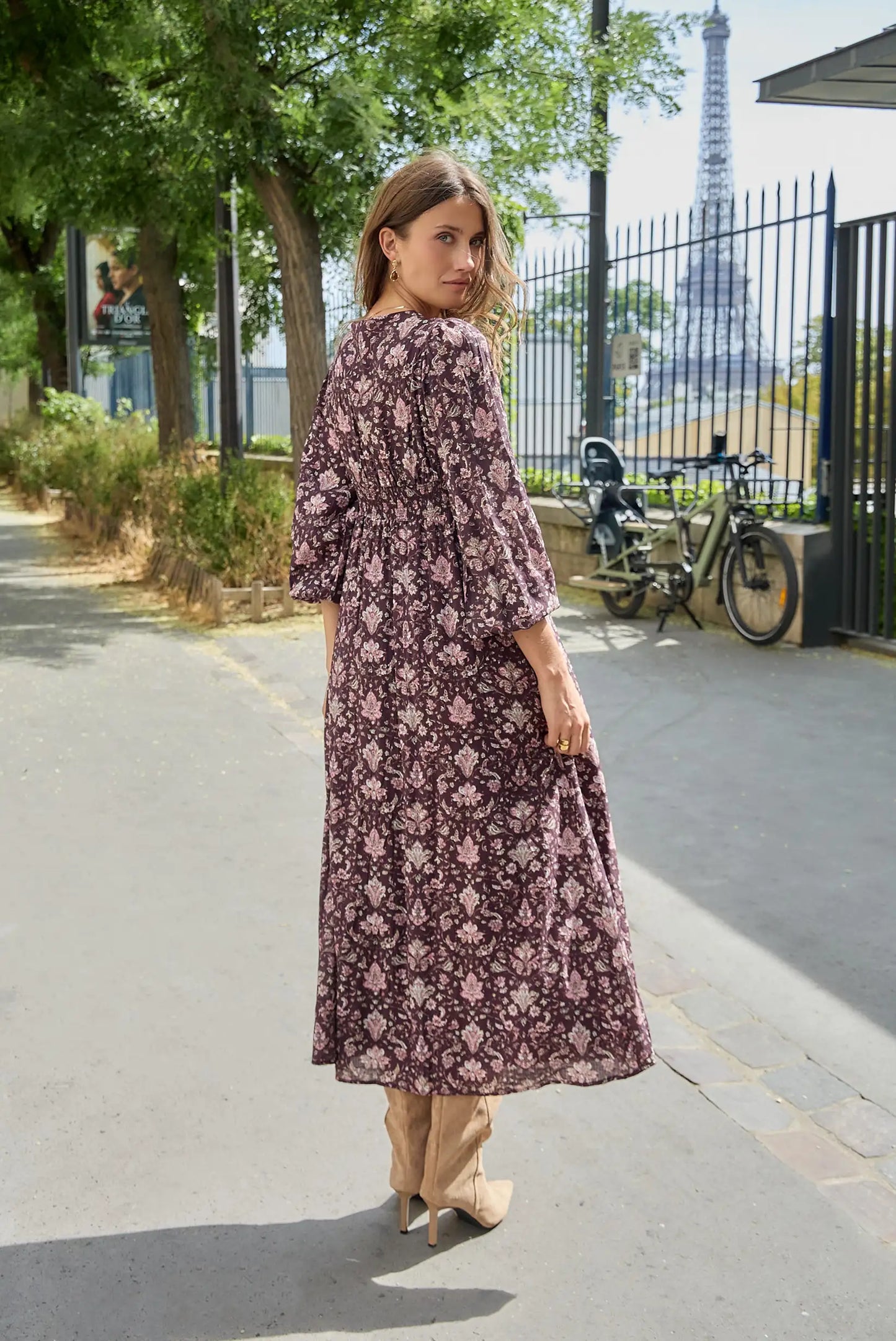 Mujer con vestido largo floral color burdeos y botines beige con la Torre Eiffel de fondo.