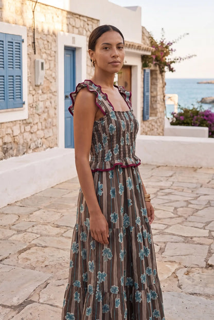 Vestido largo floral con volantes, ideal para verano y playa, con detalles en azul y marrón.