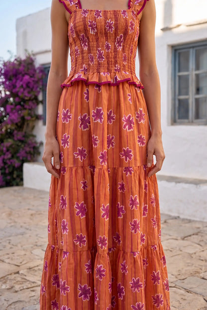 Vestido largo naranja con flores moradas, diseño con volantes y cintura elástica, ideal para verano.