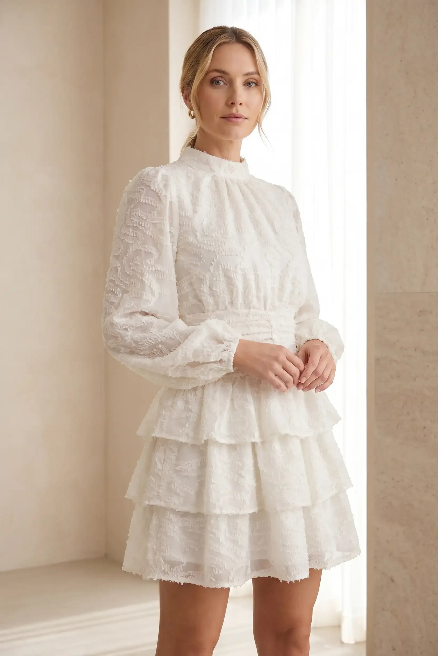 Mujer con vestido corto beige de manga larga y volantes, look veraniego elegante
