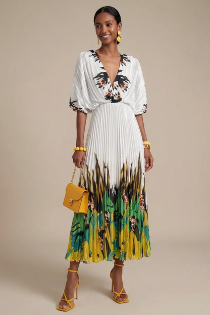 Mujer con vestido blanco plisado estampado verde tropical, bolso y sandalias amarillas.