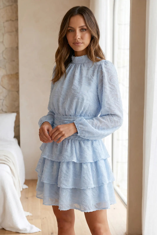 Mujer con vestido corto azul de manga larga y volantes, look primaveral, estilo casual