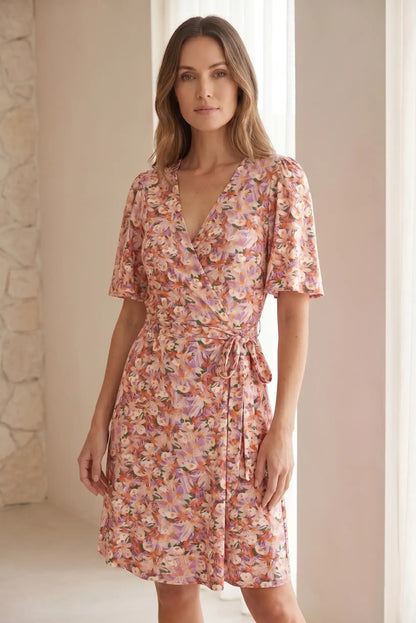 Mujer con vestido corto cruzado de flores rosas y rojas, manga corta, estilo primavera.