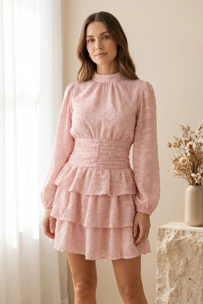 Mujer con vestido rosa corto de manga larga y textura, ideal para primavera
