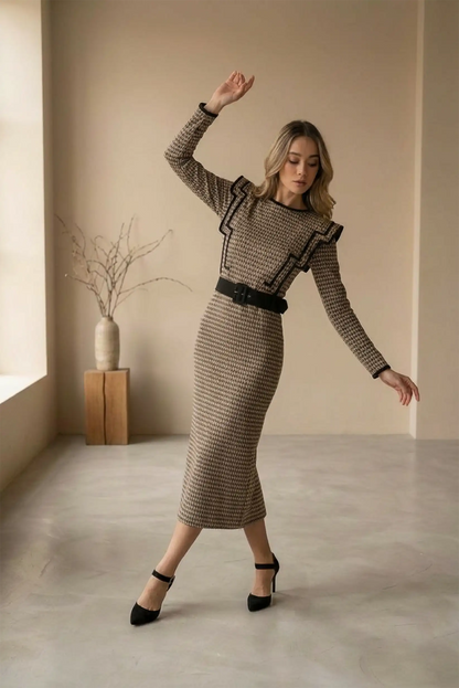 Mujer posando con vestido largo café clásico ajustado y zapatos negros de tacón en interiores minimalistas