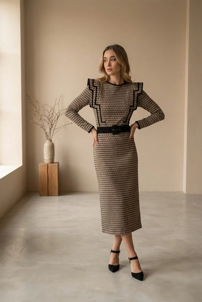 Mujer con vestido largo café clásico de manga larga y cinturón negro, en ambiente minimalista