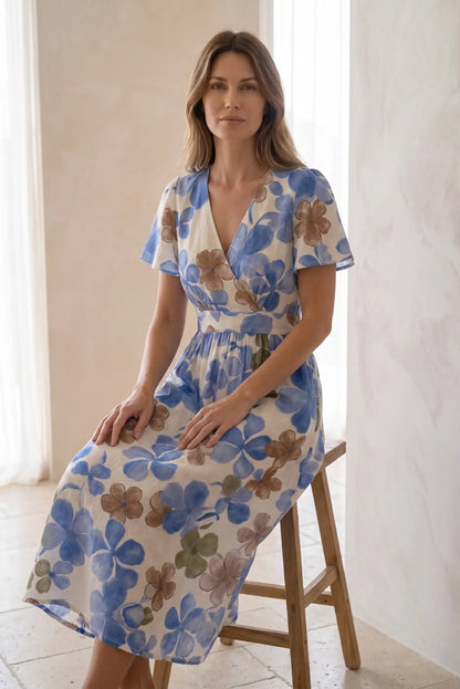 Mujer sentada con vestido largo estampado floral azul y beige, estilo primavera verano.