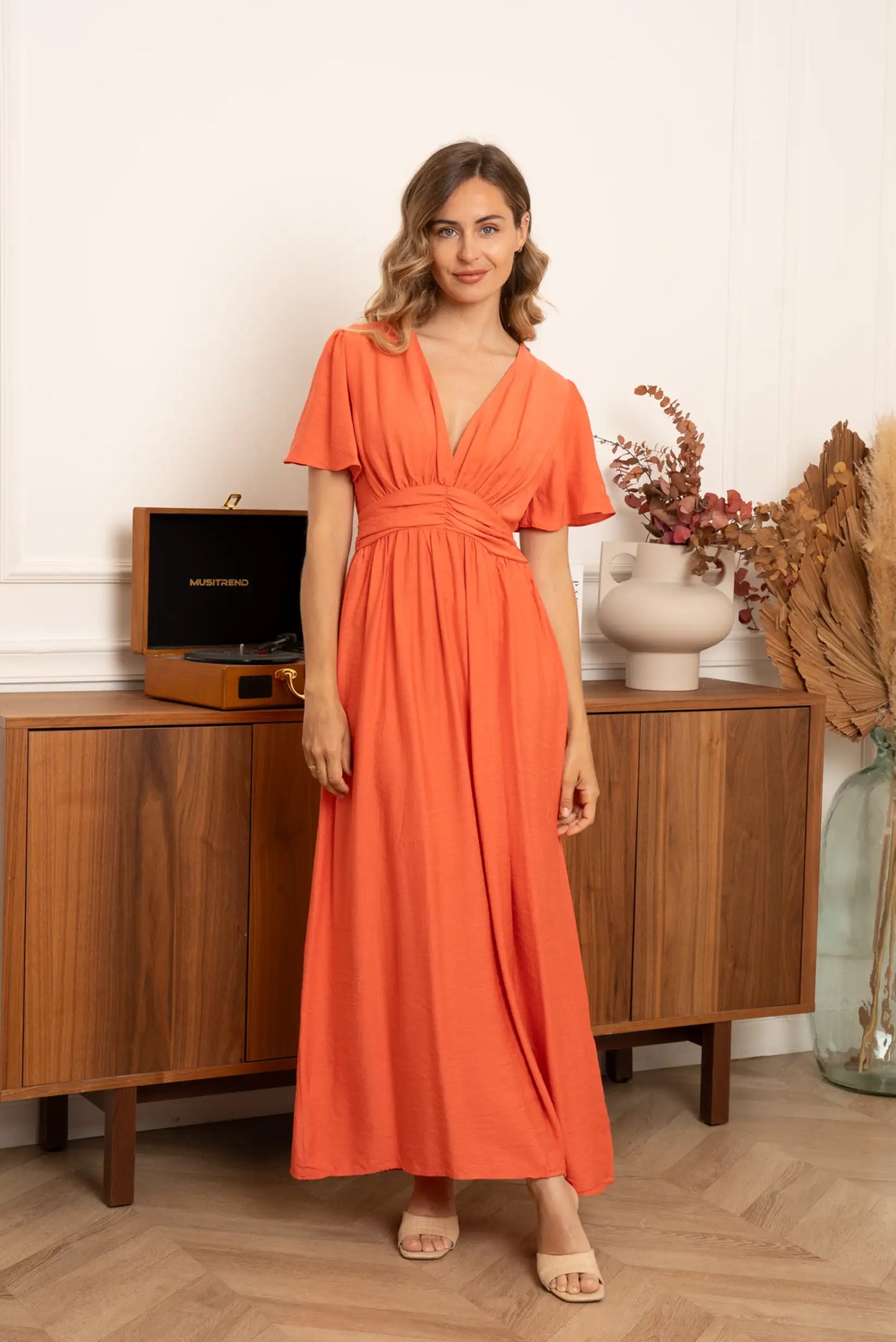 Mujer con vestido largo terracota de primavera, estilo casual, fondo decorativo de madera.