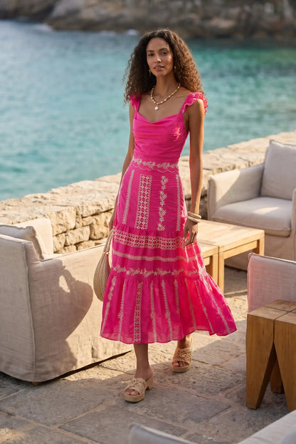 Vestido rosa con bordados blancos, ideal para verano y playa, combinado con sandalias y bolso de paja.